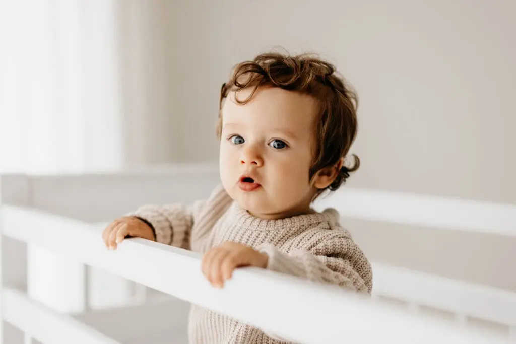 Baby steht am Gitterbett – Babyshooting im Tageslichtstudio Dunningen bei Rottweil