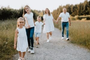 Familie mit drei Kindern bei natürlichem Familienshooting auf Feldweg im Abendlicht