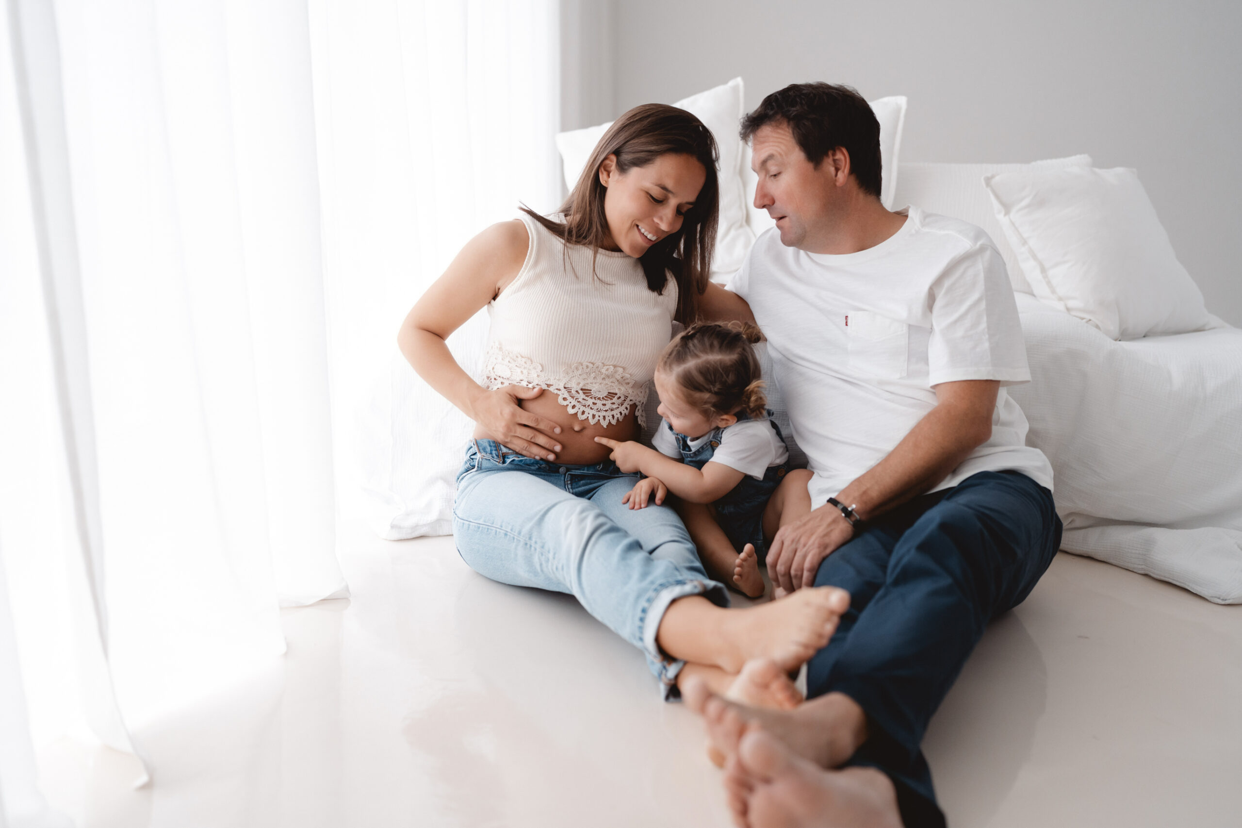 Familie sitzt im Fotostudio mit Kleinkind, Babybauchshooting, clan gehalten
